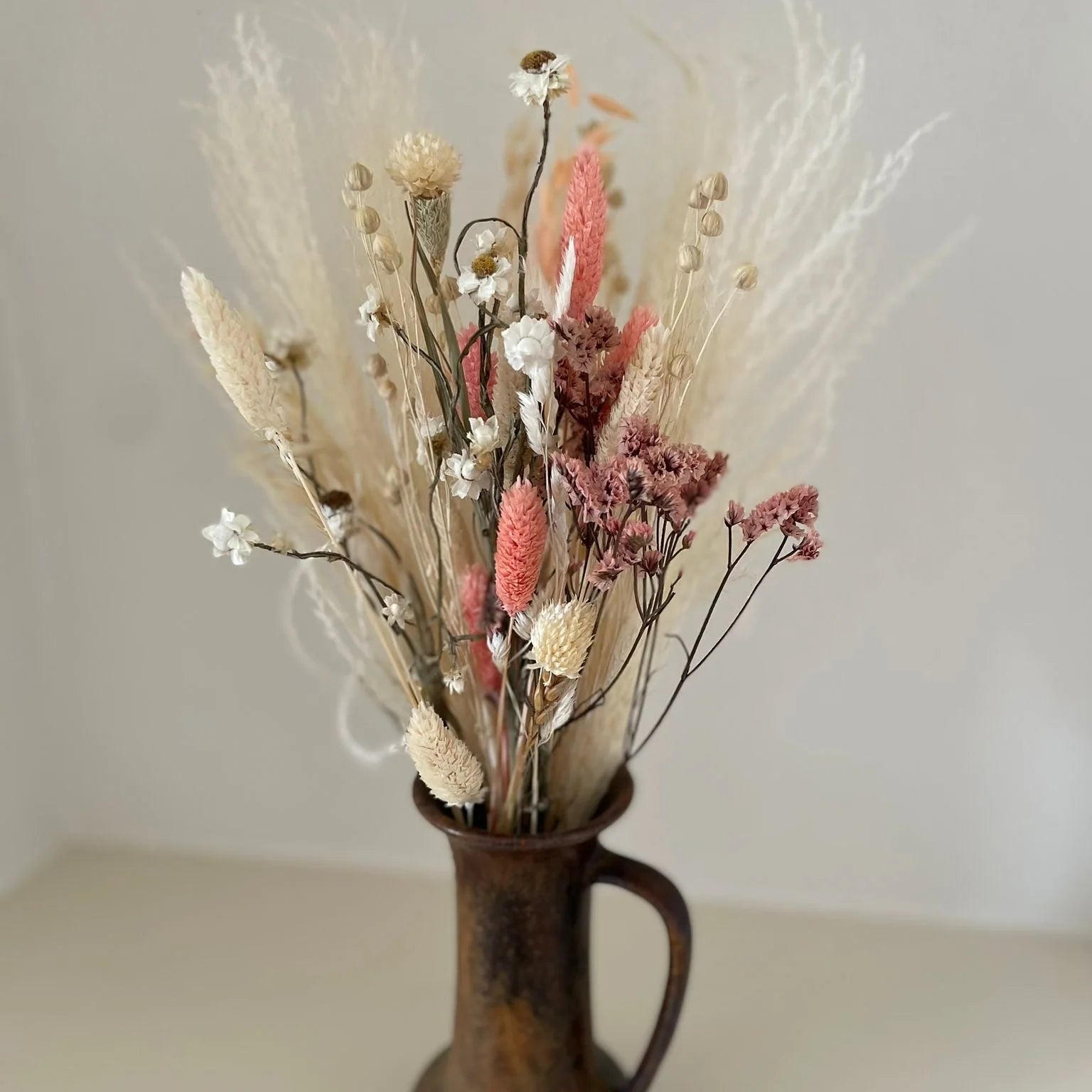 Kleiner Trockenblumenstrauß in Rosé- und Cremetönen in einer Keramikvase