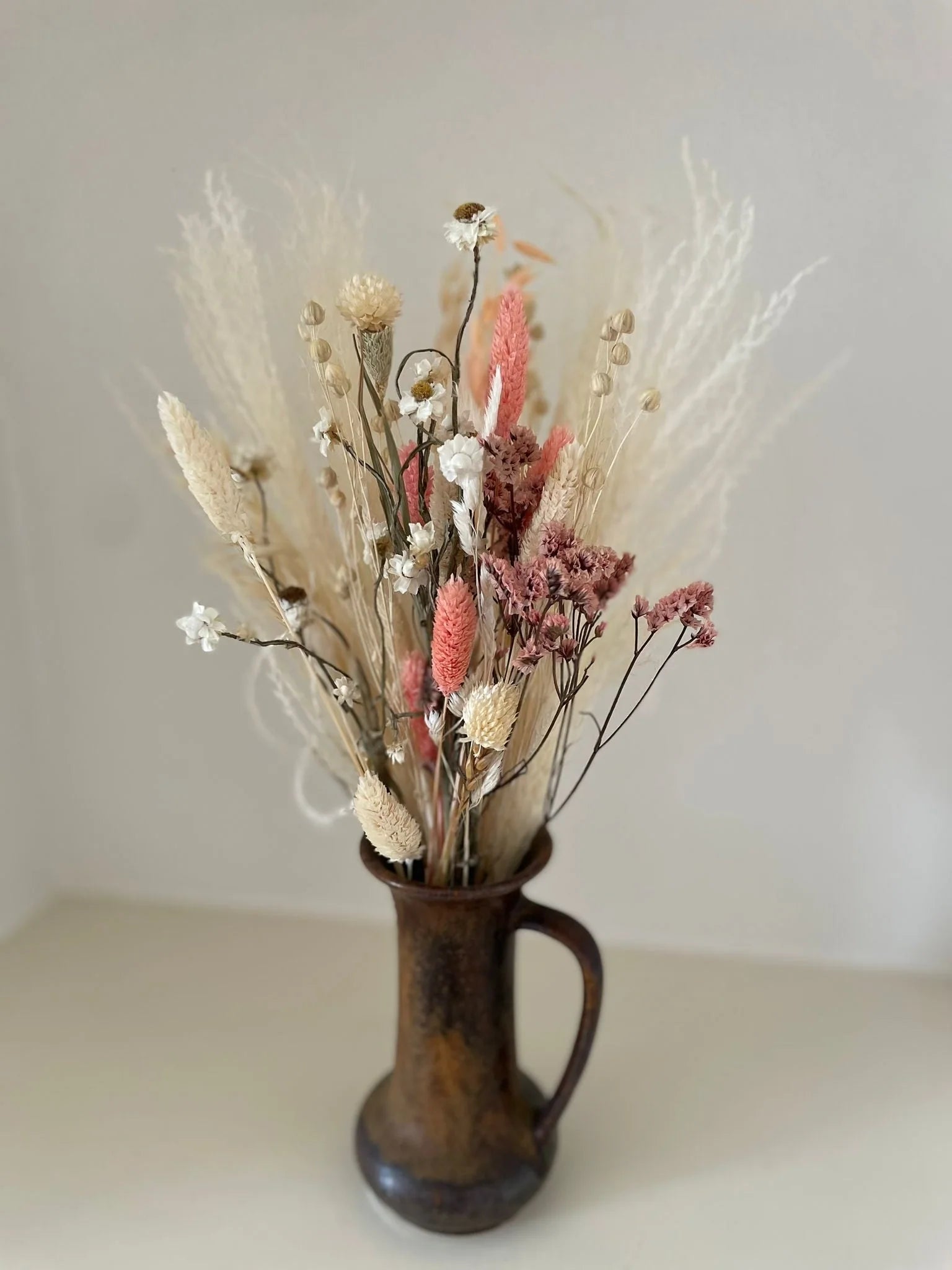 Kleiner Trockenblumenstrauß in Rosé- und Cremetönen in einer Keramikvase